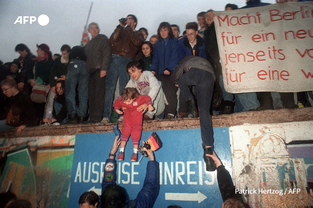 Des habitants de l'Allemagne de l'Est saluent des citoyens de l'Allemagne de l'Ouest à la porte de Brandebourg à Berlin, le 22 décembre 1989. PATRICK HERTZOG PATRICK HERTZOG - AFP