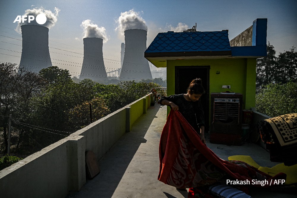 Sur cette photo prise le 6 avril 2022, une fille plie une couverture sur le toit de sa maison près de l'usine de la Thermal Power Corporation (NTPC) à Dadri. Prakash SINGH - AFP