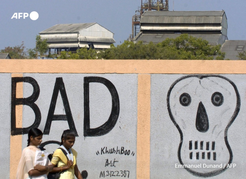 Les habitants de Bhopal marchent le long d'un mur peint d'un crâne  clôturant l'Union Carbide à Bhopal, le 29 novembre 2004. EMMANUEL DUNAND - AFP