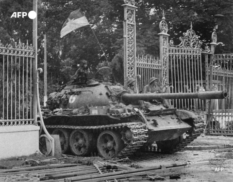 Des soldats de l'Armée nord-vietnamienne, perchés sur un char qui enfonce les grilles du palais présidentiel à Saigon, le 30 avril 1975 - AFP