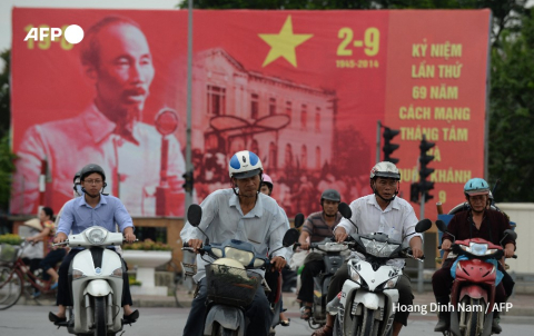 Des motocyclistes passent à Hanoï devant un portrait géant de Ho Chi Minh, le Père de l'indépendance du Vietnam, le 28 août 2014 - Hoang Dinh Nam - AFP