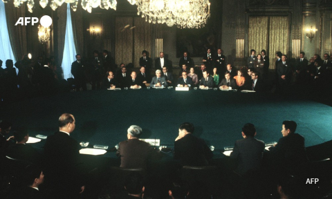 Henry Kissinger and Le Duc Tho sitting around a conference table during the signing of a peace accord between the United States, North and South Vietnam and the PRG on June 13, 1973 in Paris - AFP