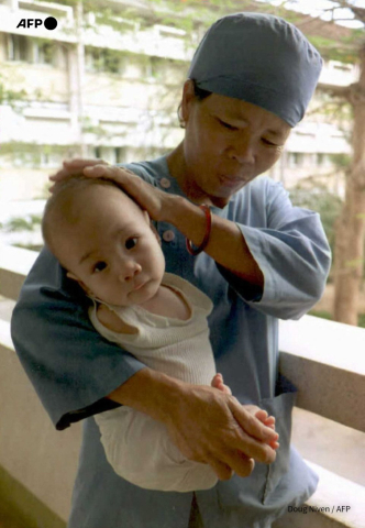 A Vietnamese nurse holds on April 27, 1995 an armless one-year-old baby at the Tu Do Hospital in Ho Chi Minh City. Doug Niven - AFP