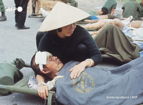 A woman comforts a seriously wounded South Vietnamese soldier waiting on the tarmac of the Phu Bai base to be transferred to Da Nang hospital in April 1972 - AFP