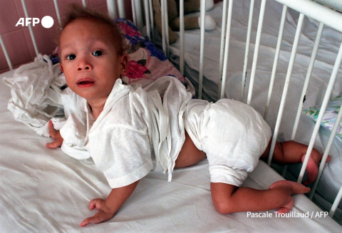 A boy suffering from hand and leg malformations crawls in his crib at the Agent Orange Victims Service in Ho Chi Minh City's Tu Du Hospital on November 17, 1998 - Pascale Trouillaud - AFP