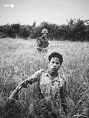 A US Marine guards a Vietcong prisoner as they walk to a collection point on October 10, 1965, in Vietnam - AFP