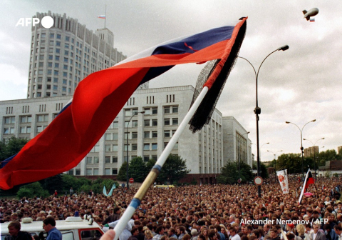 Un drapeau russe est agité au-dessus des personnes participant à un cortège funèbre pour les victimes du coup d'État devant la Maison Blanche russe à Moscou le 24 août 1991, après l'échec de la tentative de putsch  - Alexander Nemenov - AFP 