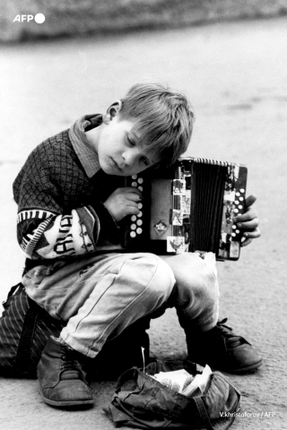 Un jeune garçon gagne de l'argent en jouant du concertina pour enfants au centre-ville de Moscou en mai 1994. - V.Khristoforov - ITAR-TASS-AFP