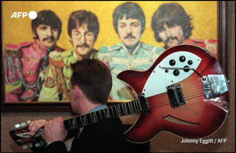 Photo de la seule guitare signée des 4 Beatles, le 15 novembre 1996, devant un tableau du groupe avant une vente aux enchères à Londres - AFP