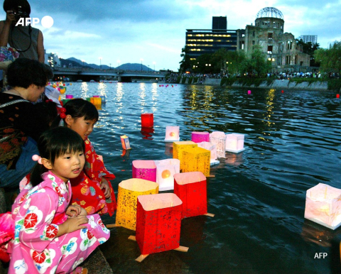 Deux fillettes lancent des lanternes flottantes sur la rivière proche des ruines du dôme d'Hiroshima le 6 août 2002 - AFP