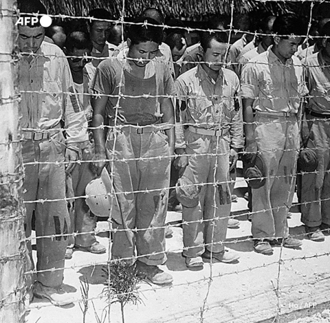 Japanese prisoners at Guam bow their heads after hearing Emperor Hirohito announce surrender, August 1945 - AFP