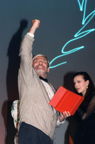 Le réalisateur français Maurice Pialat lève le poing en réponse aux sifflets du public, le 19 mai 1987 au festival de Cannes, alors qu'il vient de remporter la Palme d'or pour son film Sous le soleil de Satan. CHRISTOPHE SIMON - AFP