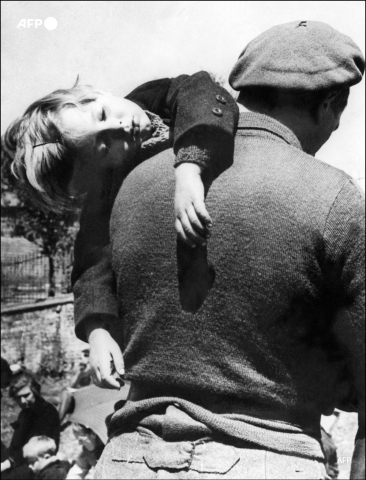 Un père emporte son enfant, fuyant les bombardements et l'arrivée des troupes allemandes en mai 1940 - AFP